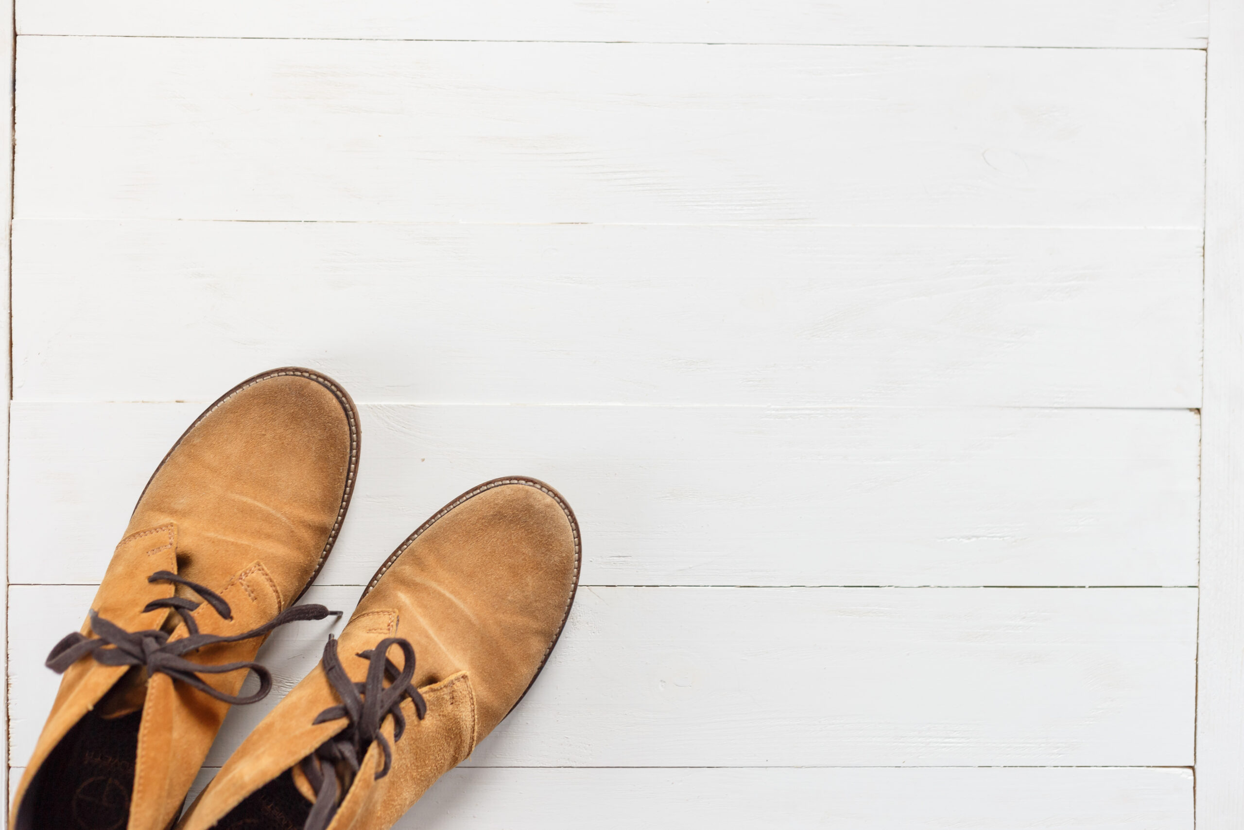 Pair of new nubuck boots on white wooden background. Top view